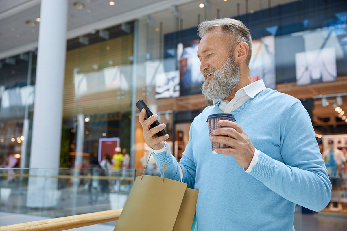 man with coffee on phone in mall